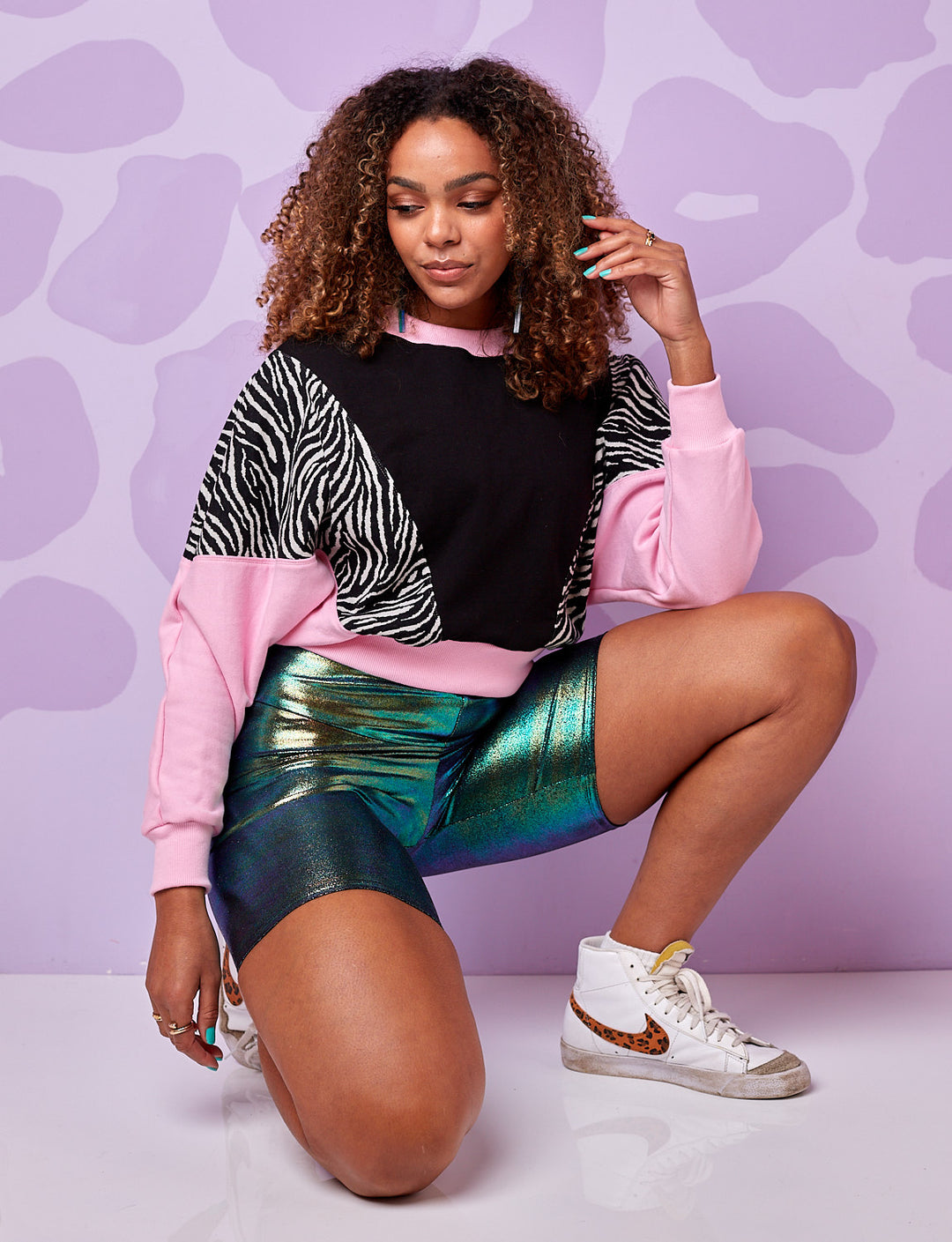 A model wearing a burnt soul cropped sweatshirt in black and white zebra print with pink and black panels and wearing blue cycling short 